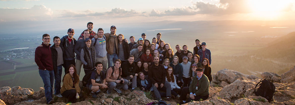 A group of DBU students smile with an Israeli valley in the background